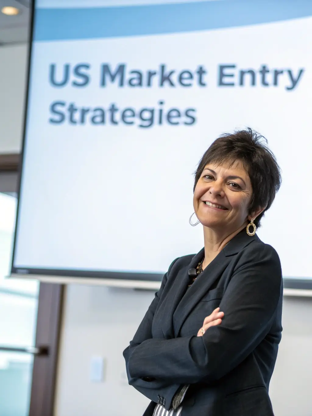 A professional headshot of a mature business coach with a warm and approachable demeanor, set against a blurred office background, conveying experience and trustworthiness.